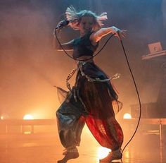 a woman is performing on stage with her hair blowing in the wind