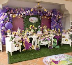 a table with purple and yellow balloons on the wall next to a green grass area