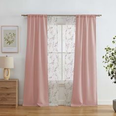 a living room with pink curtains and a plant on the side of the window sill