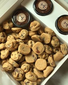 two jars of peanut butter and chocolate chip cookies in a white box on a table