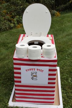 a red and white box with two rolls of toilet paper in it sitting on the grass