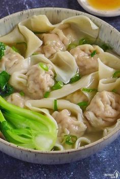 a bowl filled with dumplings and broccoli on top of a blue table