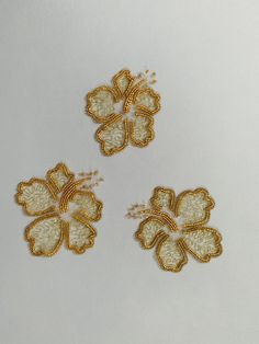 three small gold flowers on a white surface