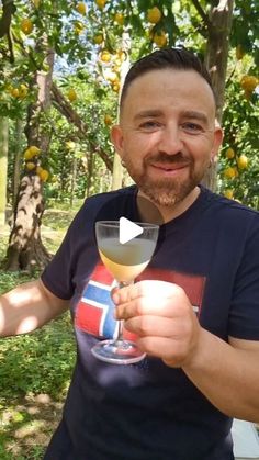 a man holding a wine glass in front of an orange tree