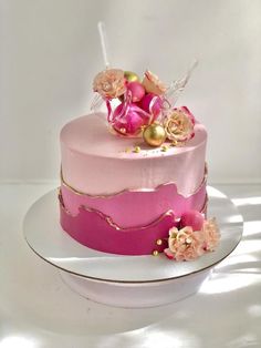 a pink and gold cake with flowers on top