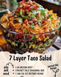 a large bowl filled with taco salad on top of a wooden table