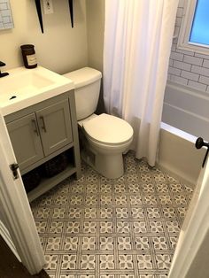 a white toilet sitting next to a bath tub under a bathroom window in a bathroom