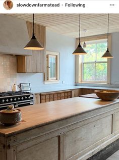 a large kitchen with an island in the middle and three lights hanging from the ceiling