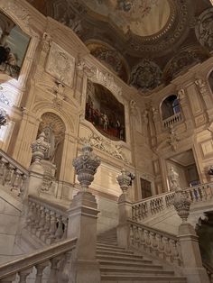 an ornate staircase in a building with paintings on the walls and ceiling above it,