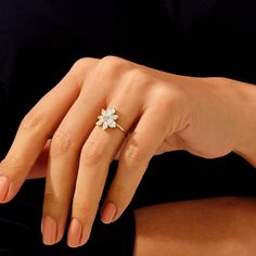 a woman's hand with a flower ring on her left hand and black background