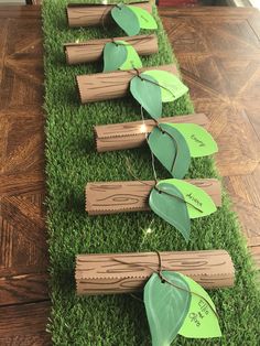 the table is set up with wooden logs and green paper leaves on top of them