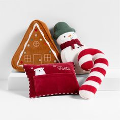 a stuffed snowman sitting next to two pillows and a gingerbread house