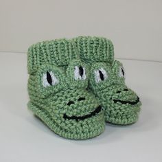 a pair of green crocheted slippers with googly eyes and mouthy mouths