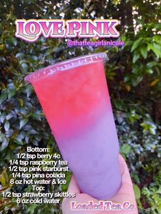 a hand holding up a pink and purple drink in front of some green bushes with the words lovepunk on it