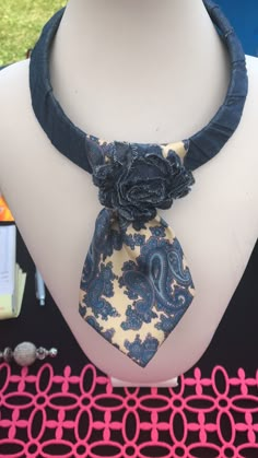 a necktie with a flower on it sitting on top of a mannequin