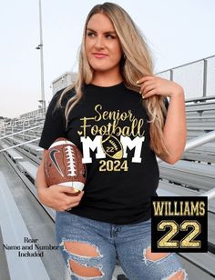 a woman holding a football and wearing a shirt that says, that's my grandson out there