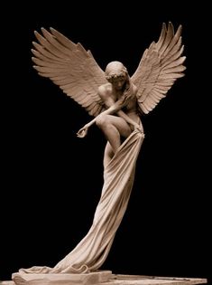 an angel statue sitting on top of a wooden table next to a black background,