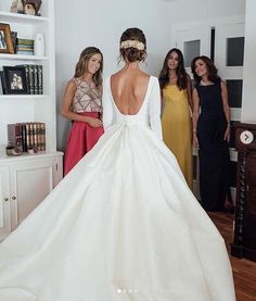 three women standing in front of a white dress