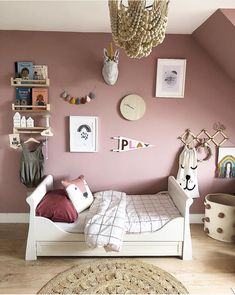 a child's bedroom with pink walls and white furniture