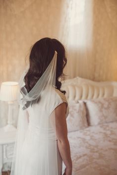 a woman in a wedding dress looking at herself in the mirror with her veil draped over her head