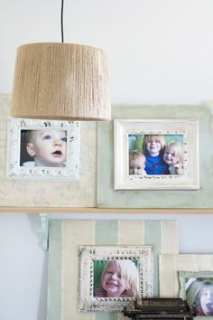 three framed pictures hang on the wall above a shelf with a lamp hanging from it