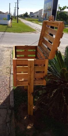 a bench made out of wooden pallets sitting on the side of a road next to a tree