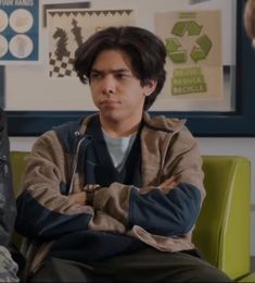 two young men sitting next to each other in a room with posters on the wall