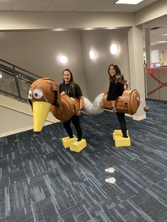 two women in costumes are posing for a photo while holding giant fake birds on their legs