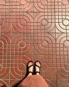 a person standing in front of a red tile floor