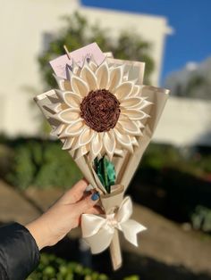 a person holding up a paper sunflower bouquet