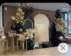 a room filled with black, gold and white balloons