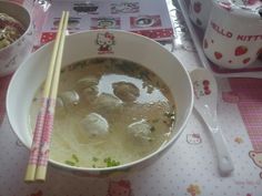 a bowl of soup and chopsticks on a table with hello kitty napkins