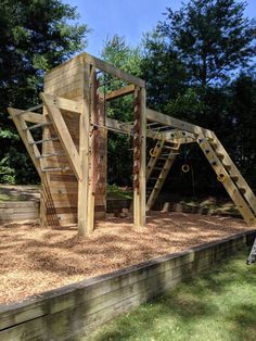 a wooden play structure in the middle of a yard