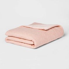 two blankets folded on top of each other in light pink linens with white piping