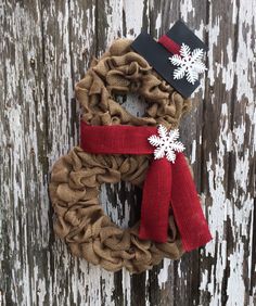 a burlock wreath with snowflakes on it hanging on a wooden door