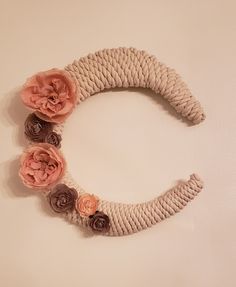 a rope wreath decorated with flowers on a white wall in the shape of a crescent