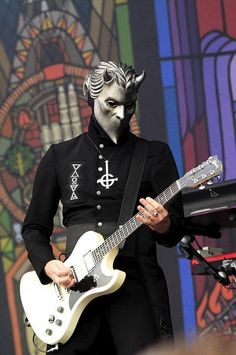 a man with white face paint playing an electric guitar