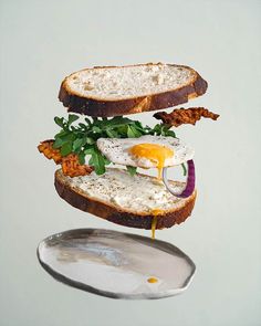 a sandwich with an egg on it is being held up by a spoon and flying through the air