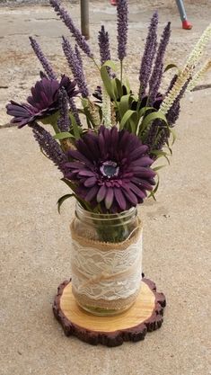 purple flowers are in a mason jar with twine