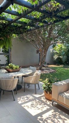 an outdoor living area with couches, tables and chairs under a pergolated roof