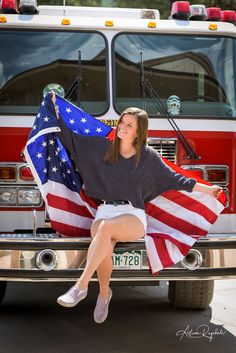 a woman sitting on the back of a fire truck with an american flag draped over her shoulders