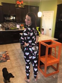 a woman standing next to a dog in a kitchen