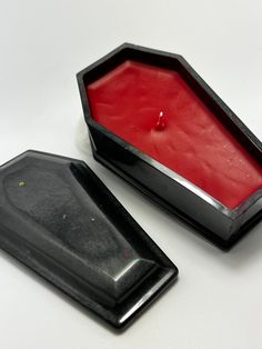 two black trays with red wax in them sitting on a table top next to each other