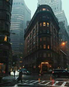 people are crossing the street at night on a rainy day in new york's financial district