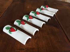 four white dishes with strawberries painted on them sitting on a wooden table, ready to be eaten