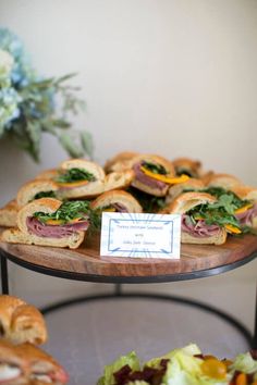 sandwiches and salads are displayed on three tiered trays, each with a name card