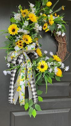 a wreath with sunflowers, daisies and greenery hangs on the front door