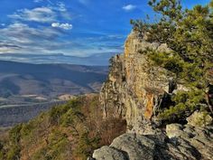 a view from the top of a mountain looking down at some trees and mountains in the distance