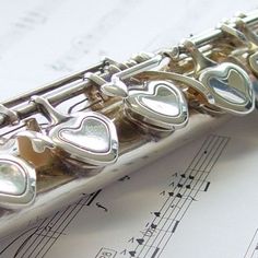 a silver flute with hearts on it and sheet music