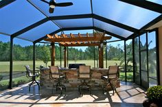 a covered patio with tables and chairs under a blue sky shade structure that has a ceiling fan on it